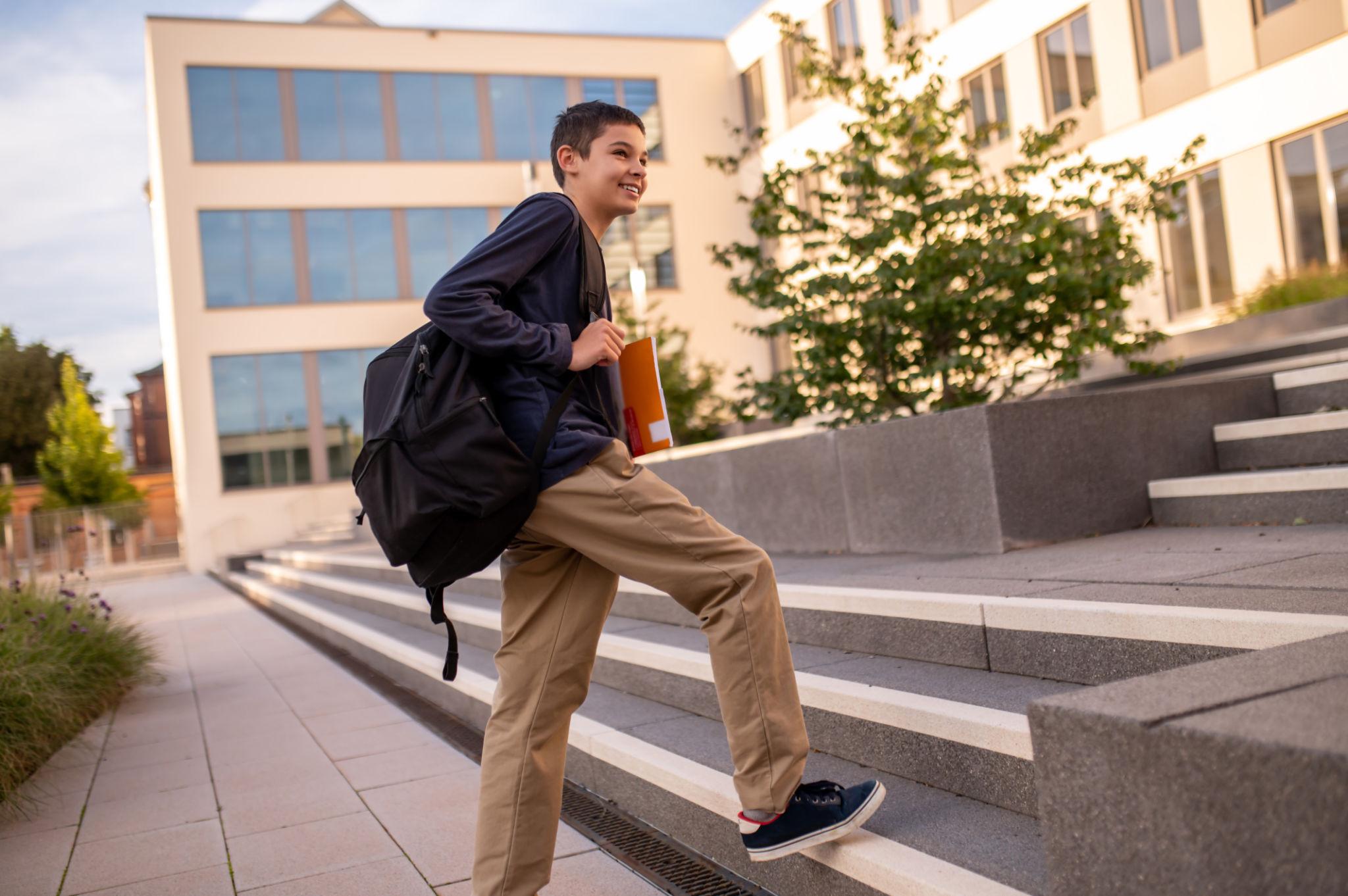 A student with a school bag confidently climbing steps — representing the energy and momentum of showing up every day